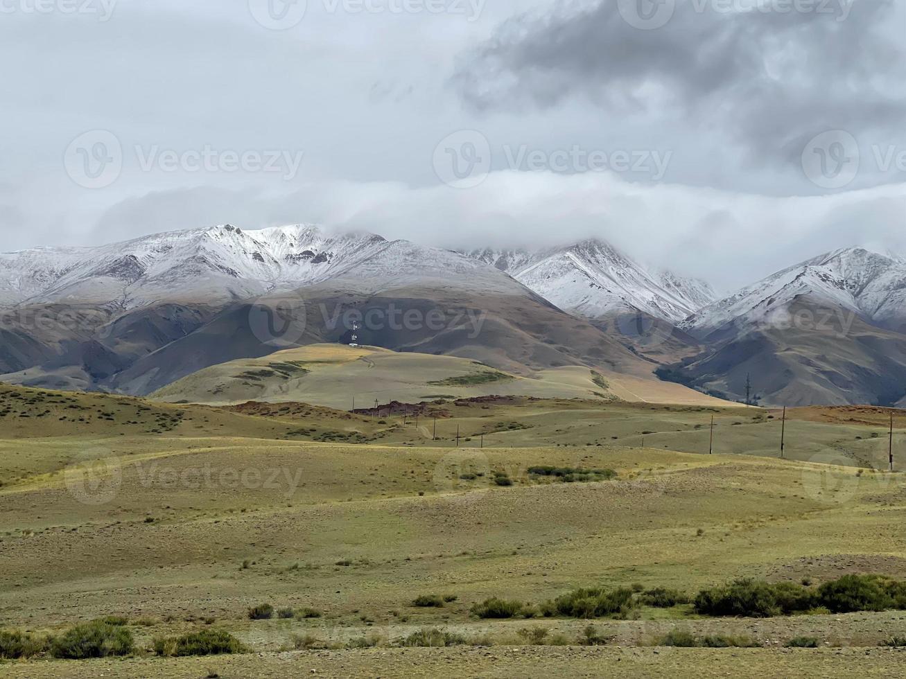 wolken, die auf den spitzen der schneebedeckten berge im altai-gebirge liegen foto