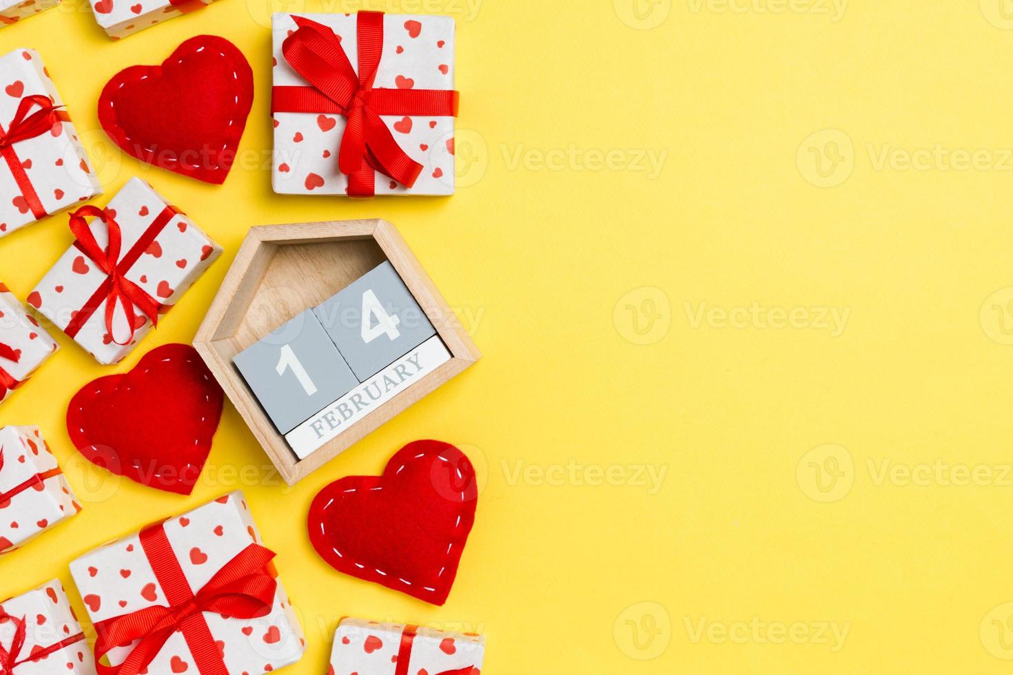 Draufsicht auf Geschenkboxen, Holzkalender und rote Textilherzen auf buntem Hintergrund. der vierzehnte februar. Valentinstag-Konzept mit Kopierraum foto