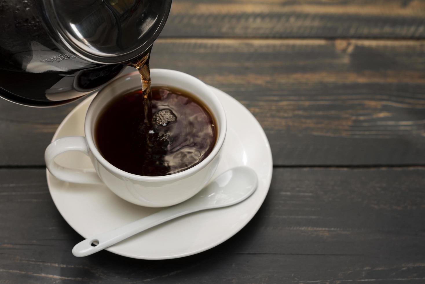 weiße Kaffeetasse mit schwarzem Kaffee oder Tee. auf Schreibtisch oder Lesetisch stellen - Ansicht von oben foto