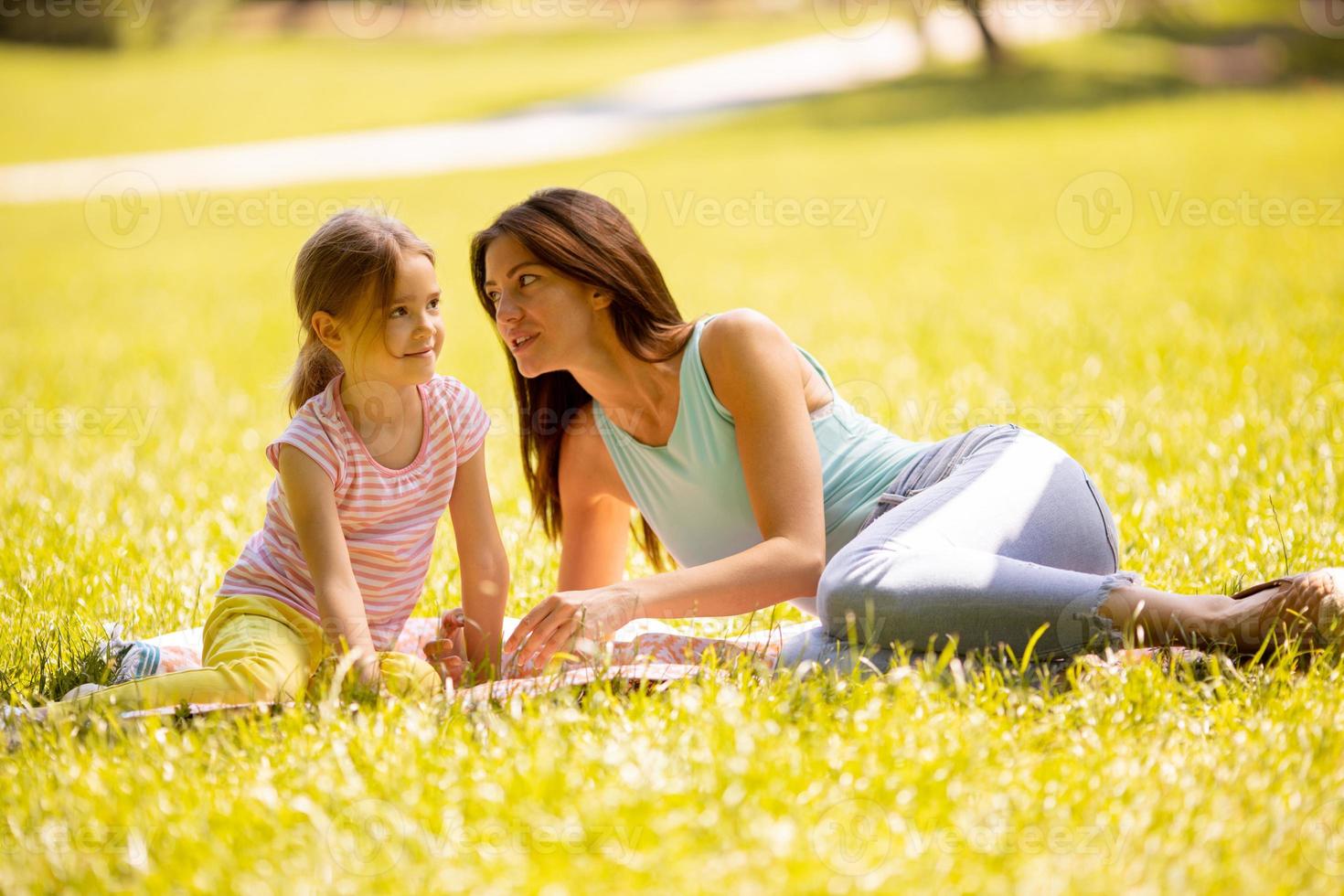 Mutter mit kleiner Tochter, die sich an einem sonnigen Tag im Park amüsiert foto