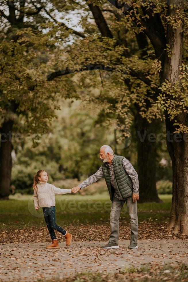 Großvater verbringt am Herbsttag Zeit mit seiner Enkelin im Park foto