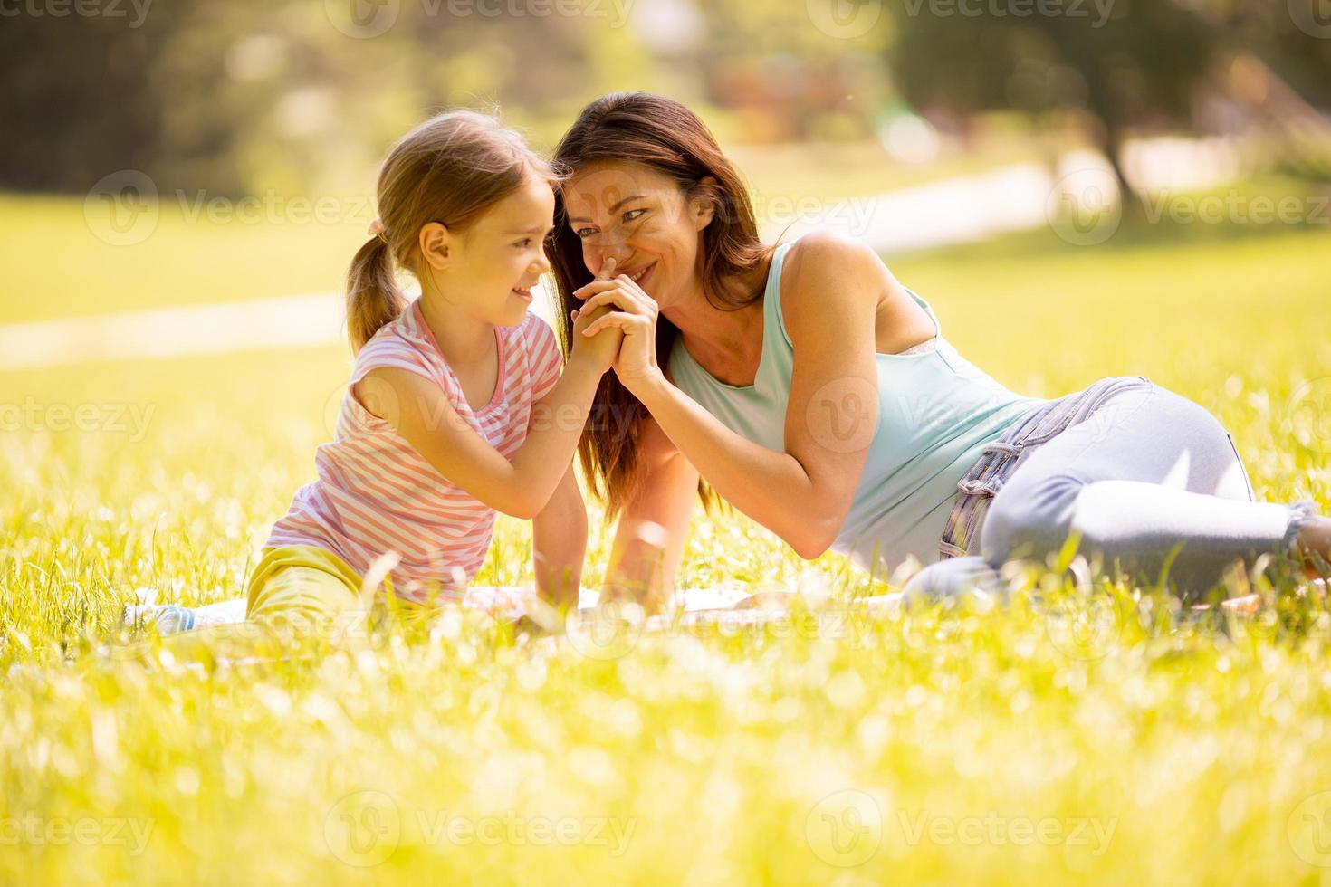 Mutter mit kleiner Tochter, die sich an einem sonnigen Tag im Park amüsiert foto