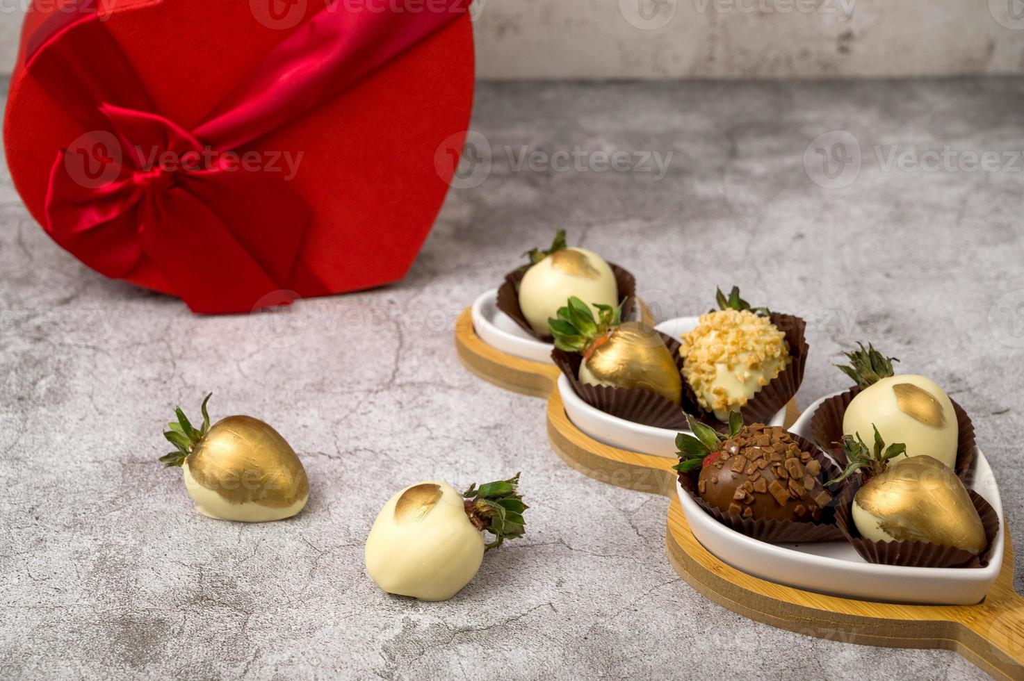 herzförmige schachtel mit verschiedenen erdbeeren mit schokoladenüberzug auf grauem hintergrund. st valentinstag konzept foto
