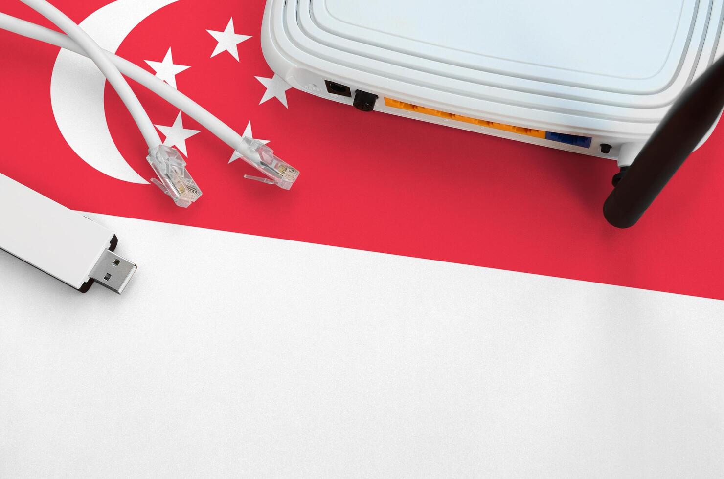 Singapur-Flagge auf dem Tisch mit Internet-RJ45-Kabel, drahtlosem USB-WLAN-Adapter und Router. Konzept der Internetverbindung foto