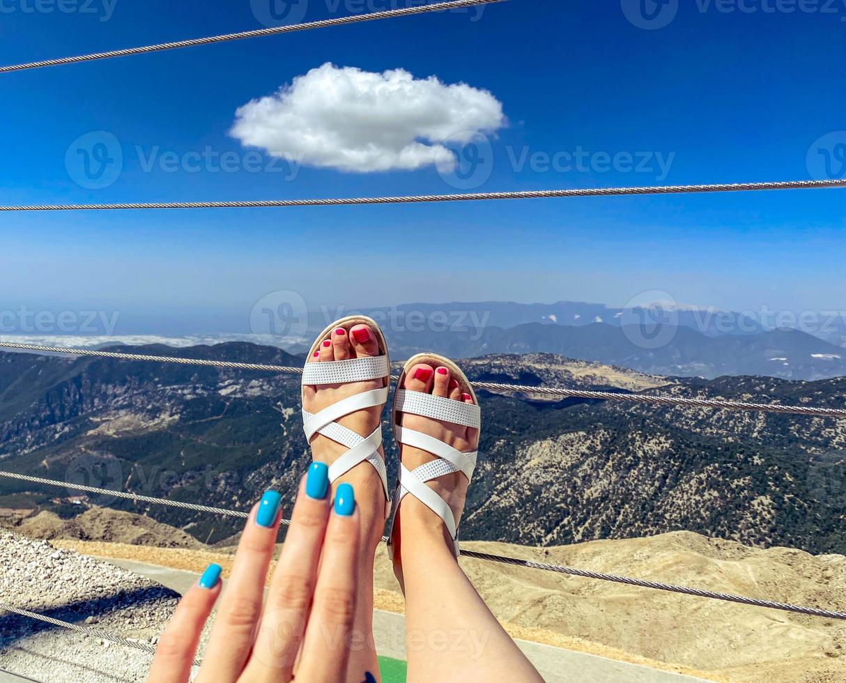 Füße mit einer knallpinken Pediküre in weißen Ledersandalen. Schuhe aus natürlichen Materialien. Mädchen mit Maniküre und Pediküre im Urlaub foto