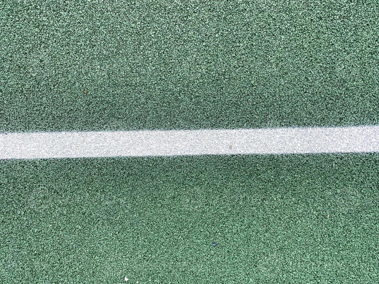 Grüne Gummioberfläche einer antitraumatischen Sicherheitsfliese eines Tennisplatzes auf einem Sportspielplatz in einem öffentlichen Park oder Innenhof. der Hintergrund. Textur foto