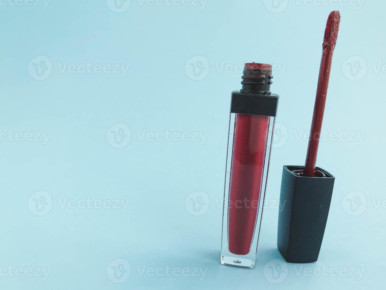 Lippenstift auf einem blauen, hellen, matten Hintergrund. Lippenstift in einem trendigen, stylischen Beerenrotton. Lipgloss mit einem weichen und bequemen Lippenpinsel foto