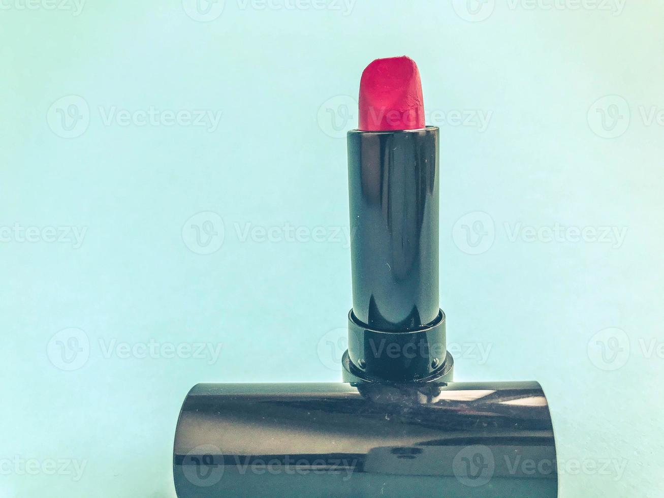 Lippenstift auf einem blauen, hellen, matten Hintergrund. lippenstift im trendigen, stylischen farbton rot. Kompakter Lippenstift in einer schwarzen Tube. stilvolles und trendiges Retro-Make-up foto