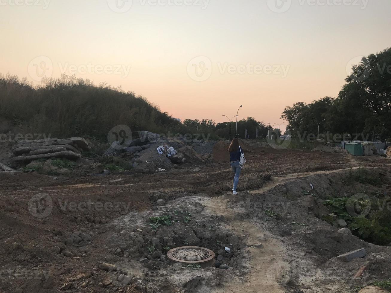 Bau eines neuen Mikrobezirks im Stadtzentrum. Ein Mädchen mit langen dunklen Haaren geht durch einen Sandsteinbruch. Ein Mädchen läuft auf einer verlassenen Baustelle foto