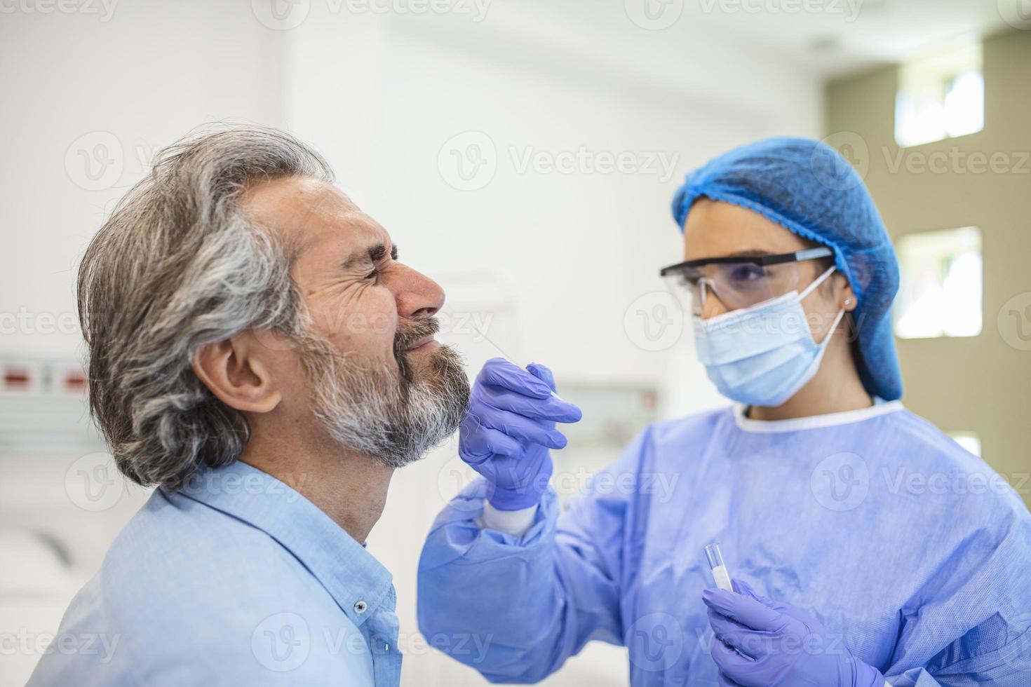 medizinisches Personal mit Schutzausrüstung führt Coronavirus-Tupfer bei älteren Männern durch. Nasenabstrich für Covid-19. foto