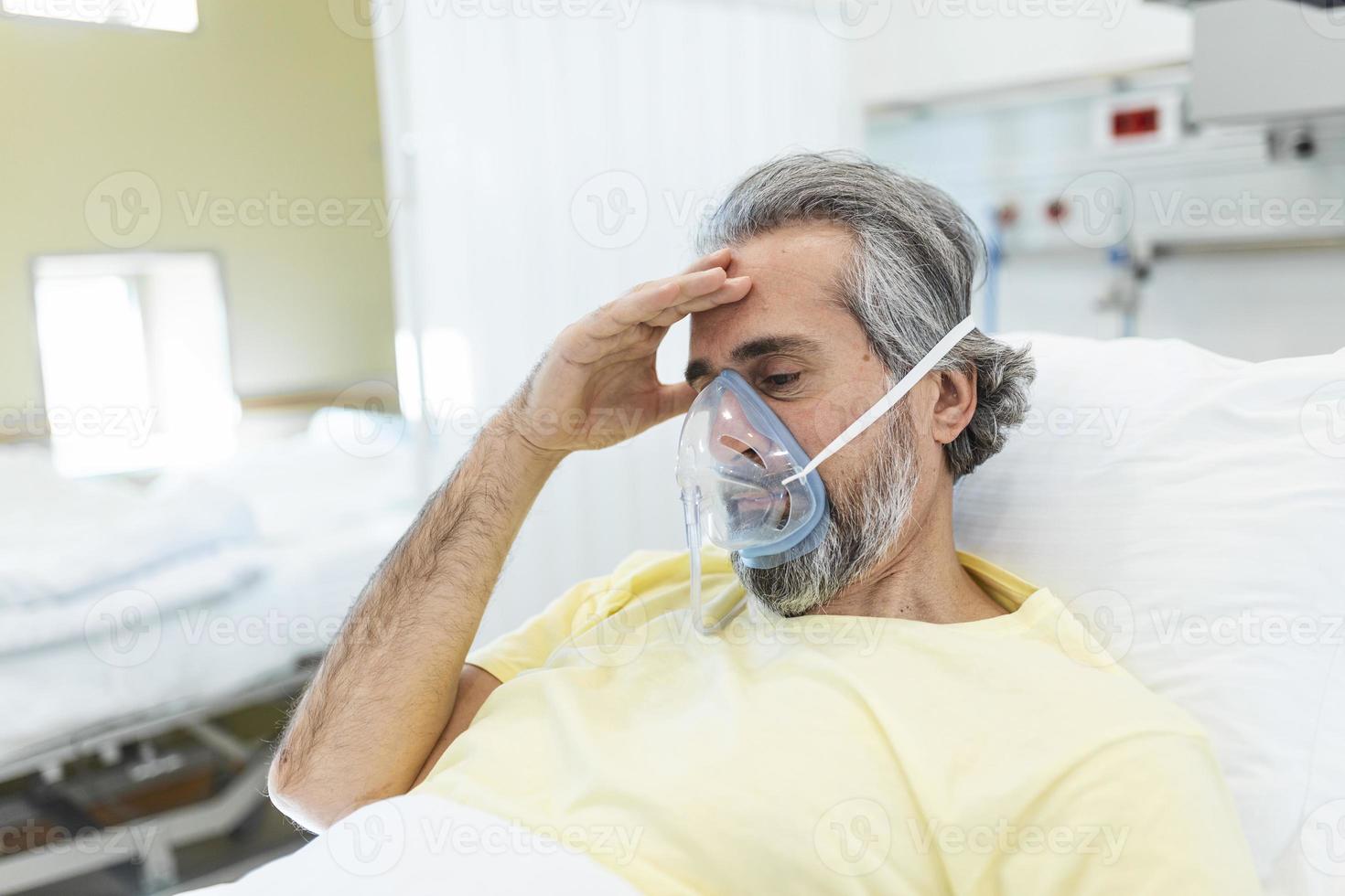 männlicher Coronavirus-Patient, der wegschaut, während er sich auf dem Krankenhausbett ausruht. Mann trägt Sauerstoffmaske. Er ist während der Pandemie im Krankenhaus. foto