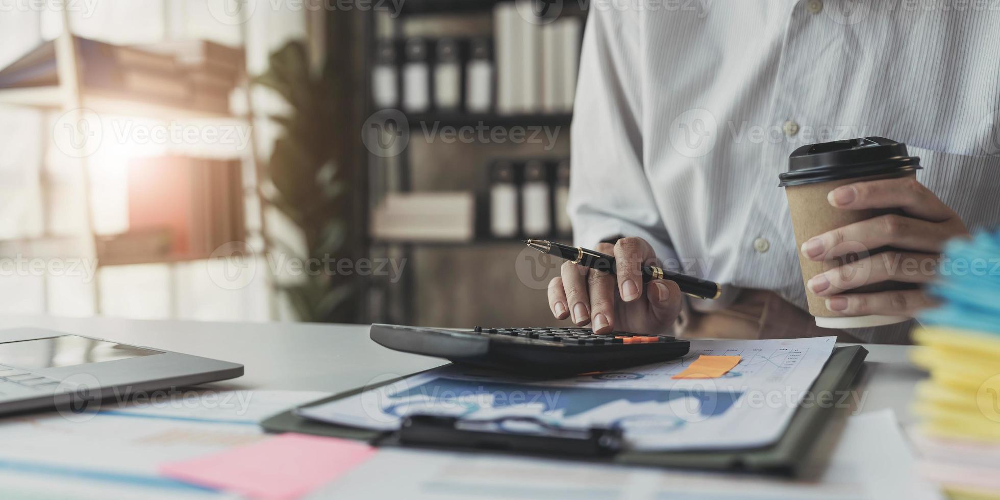 Geschäftsfrau mit Taschenrechner für Mathe-Finanzierung auf Holzschreibtisch im Büro- und Geschäftshintergrund, Steuern, Buchhaltung, Statistik und analytisches Forschungskonzept foto