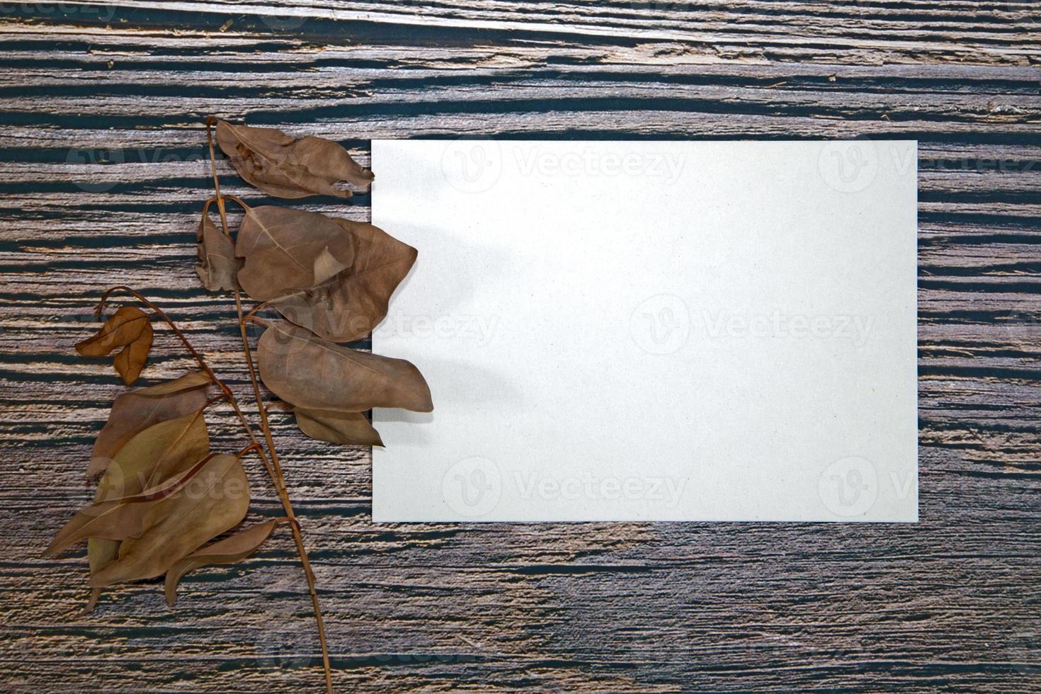 a5-papiergrußkartenmodell mit trockenen blättern auf holzhintergrund foto