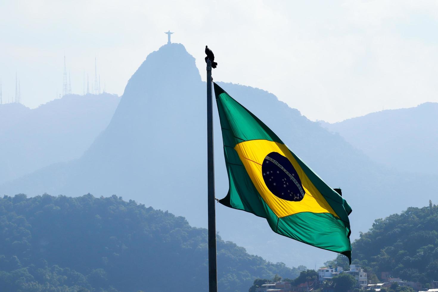 rio de janeiro, rj, brasilien - 27. april 2022 - brasilianische flagge winkt mit corcovado-hügel und christus die erlöserstatue im hintergrund - duque de caxias fort, leme-viertel foto