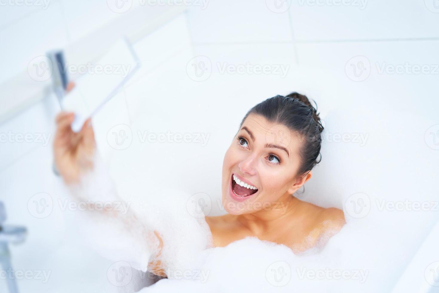 junge nette brünette frau, die bad in der badewanne hat foto