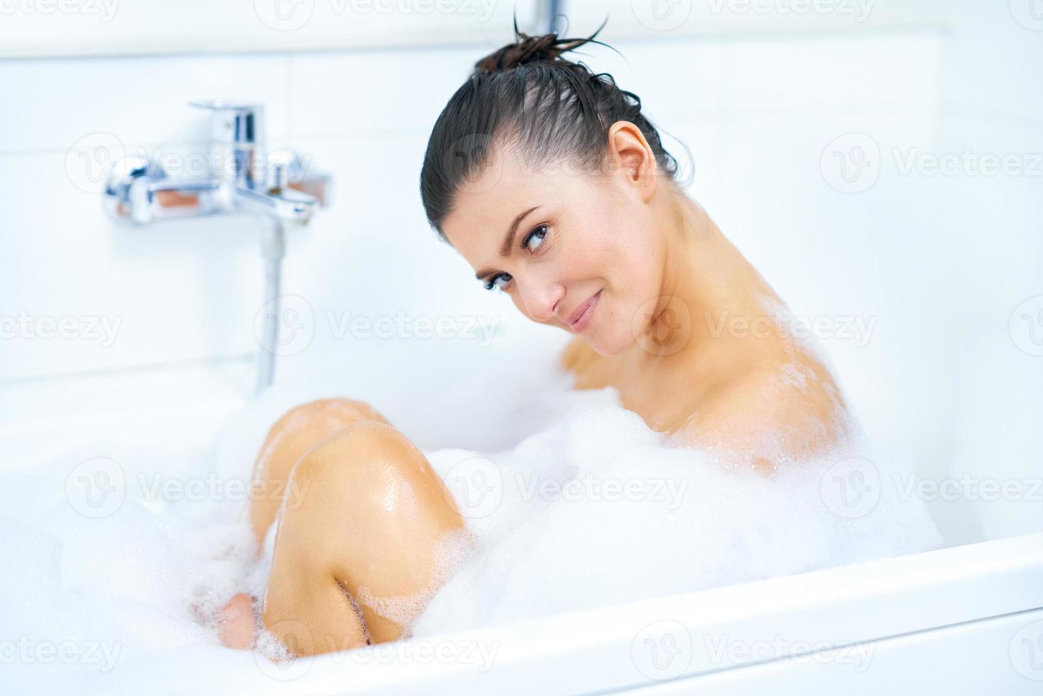 junge nette brünette frau, die bad in der badewanne hat foto