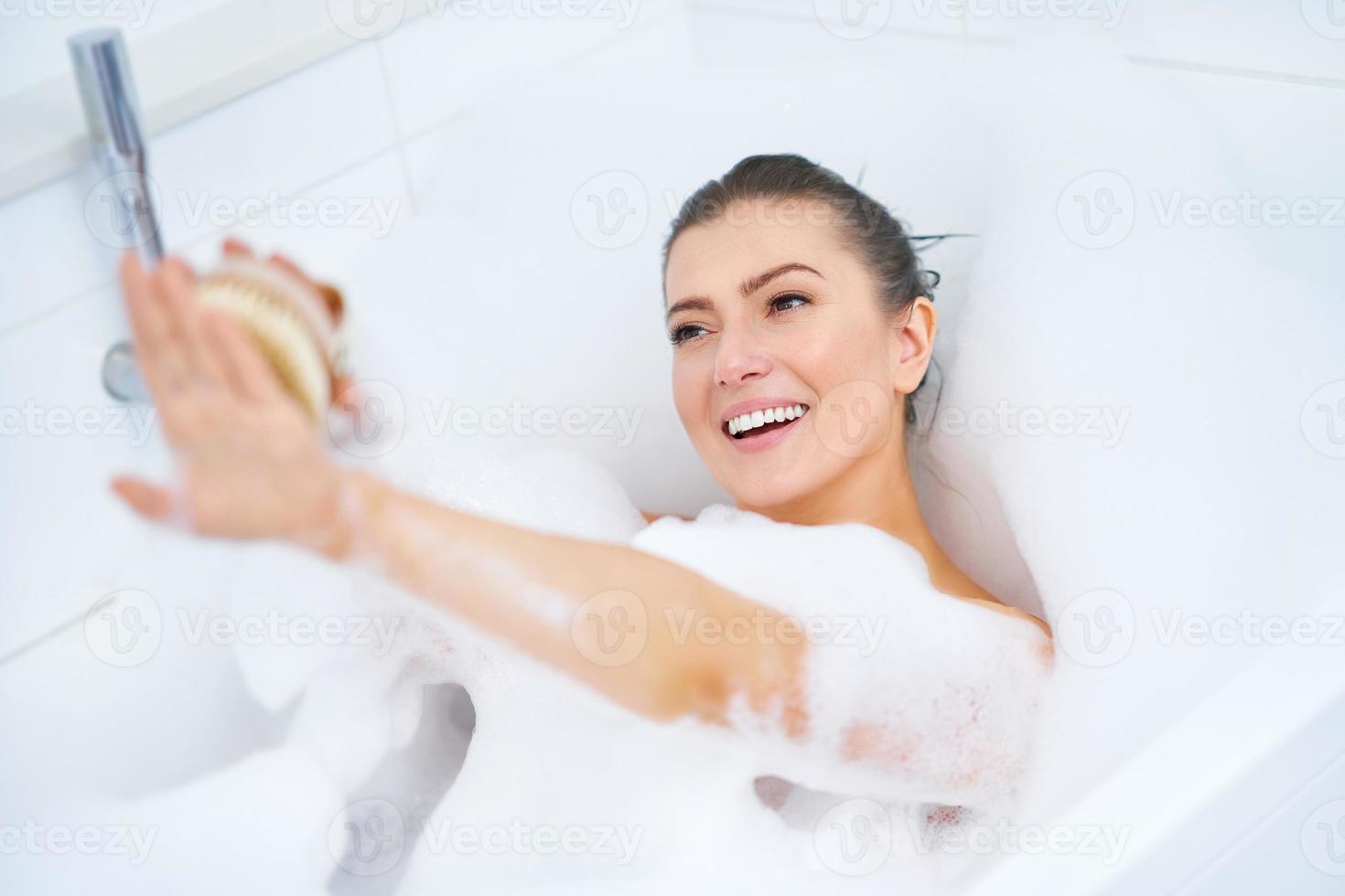 junge nette brünette frau, die bad in der badewanne hat foto