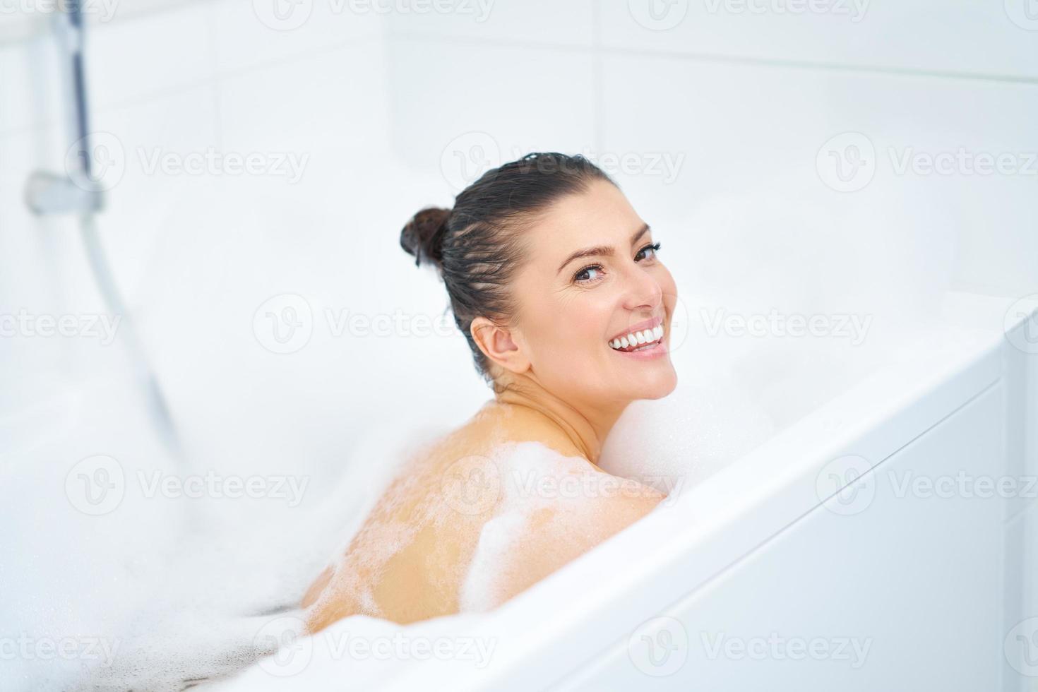 junge nette brünette frau, die bad in der badewanne hat foto