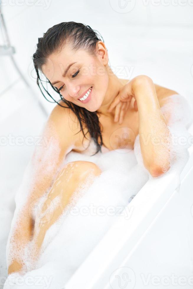 junge nette brünette frau, die bad in der badewanne hat foto