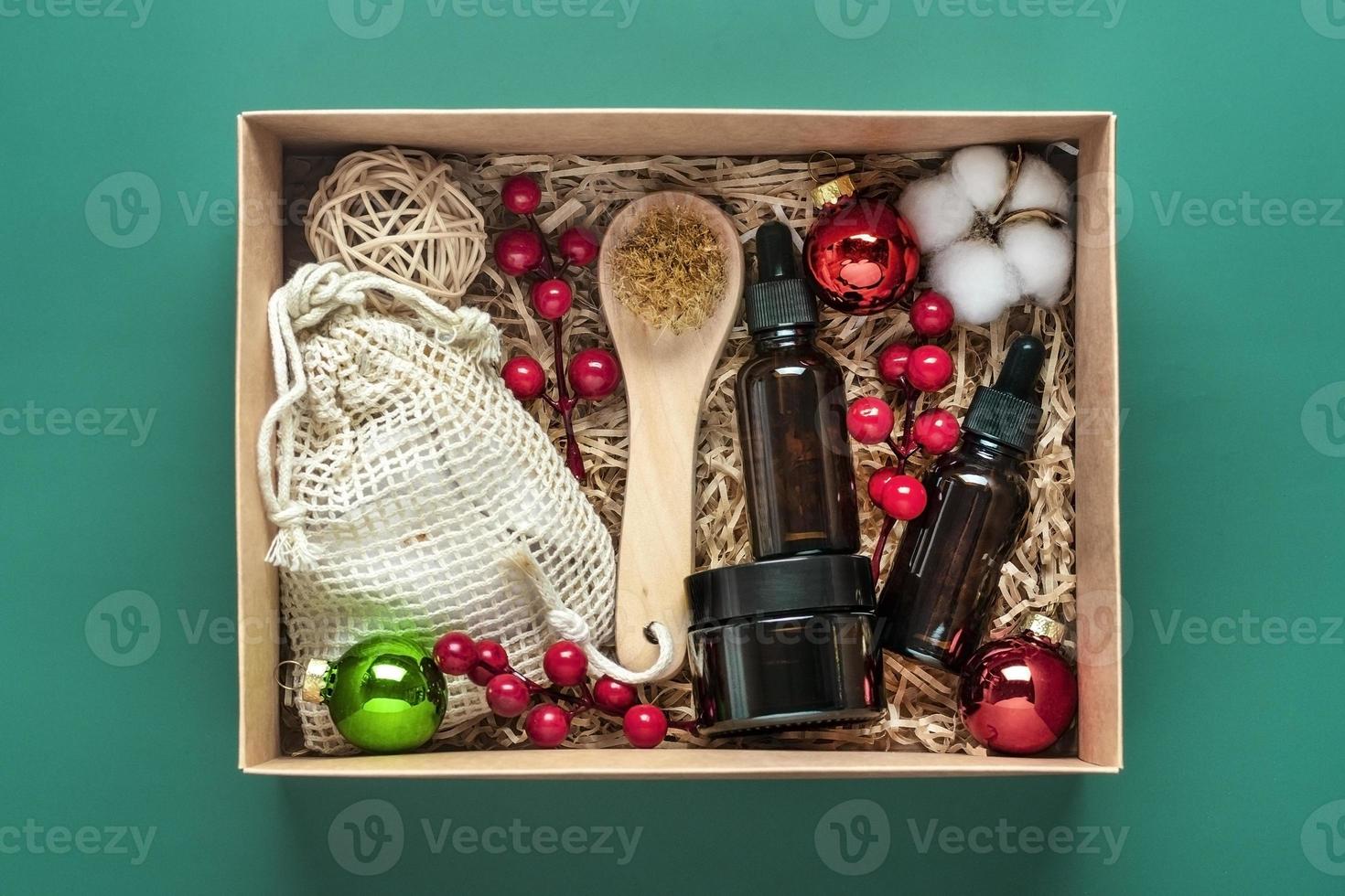 set für pflegebox umweltfreundliche kosmetiköl- und cremeflaschen, bürste zum waschen, wattepads auf grünem hintergrund geschenk für freundin, mutter zur feier des weihnachtskonzepts draufsicht flach liegend foto