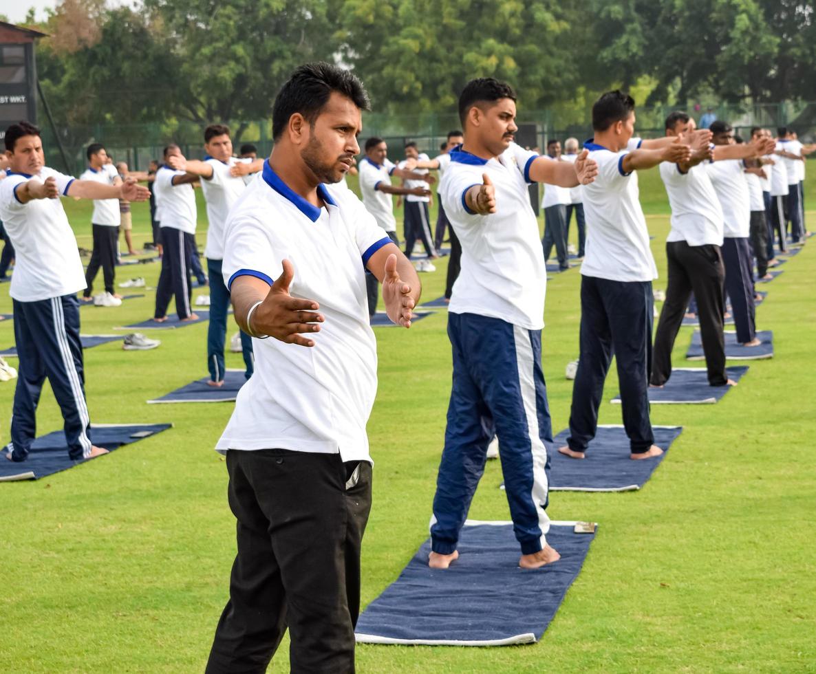 neu-delhi, indien, 21. juni 2022 - gruppen-yoga-übungssitzung für menschen im yamuna-sportkomplex in delhi am internationalen yoga-tag, große gruppe von erwachsenen, die an yoga-kursen im cricket-stadion teilnehmen foto