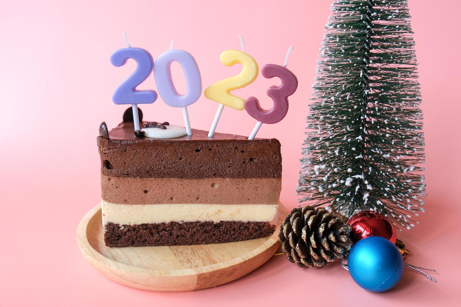 Schokoladenkuchen mit Zahlen 2023 und Zubehör für Weihnachten und Neujahr isoliert auf rosa Hintergrund. foto