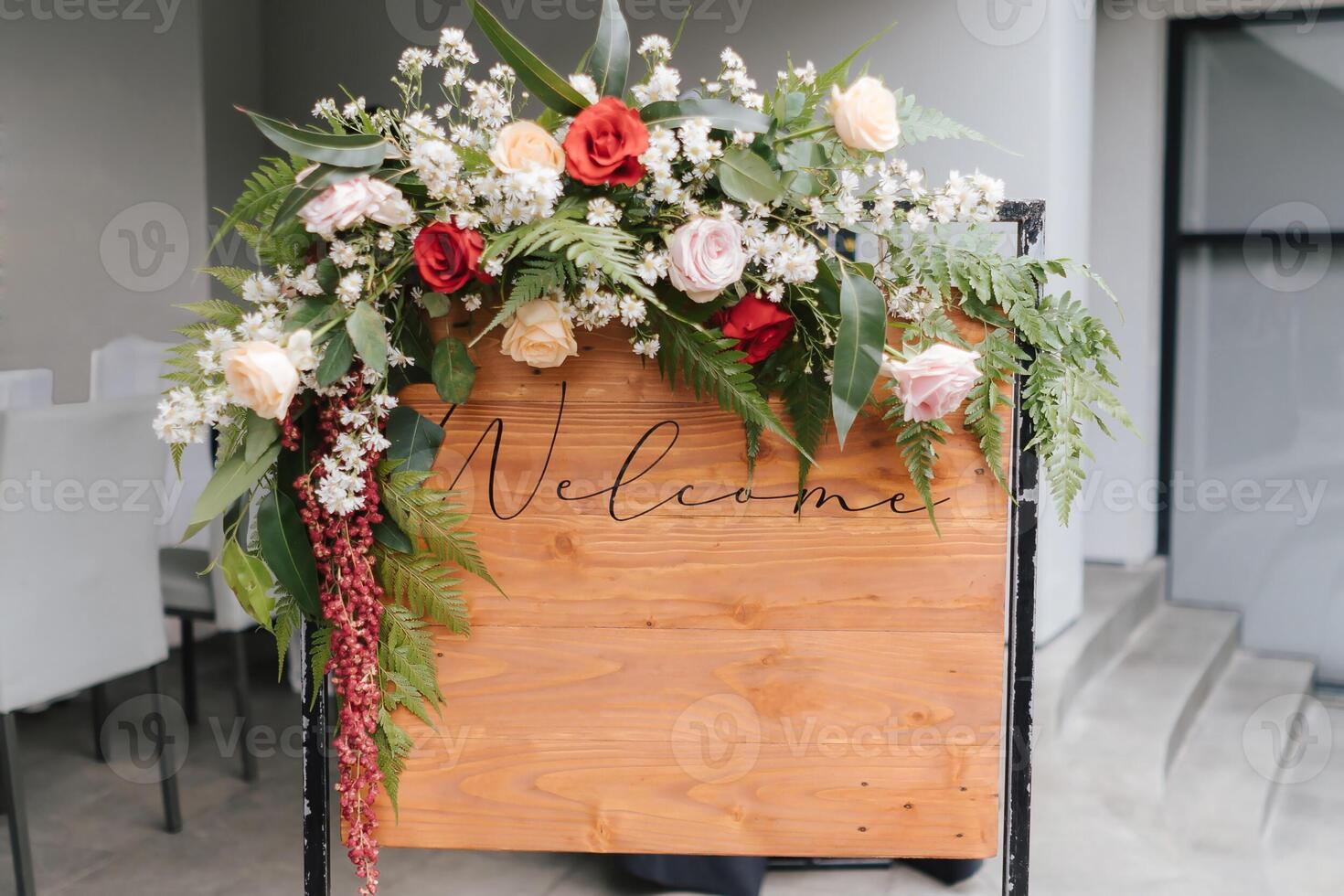 Ein Willkommensschild mit einer schönen Blumendekoration, das vor dem Hochzeitseingang steht. foto