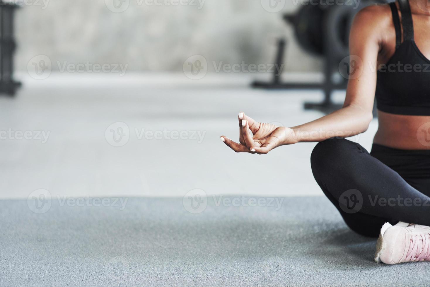 beschnittenes Foto. Partikelansicht eines sportlichen Mädchens im Fitnessstudio, das an ihren Wochenenden auf dem Boden sitzt foto