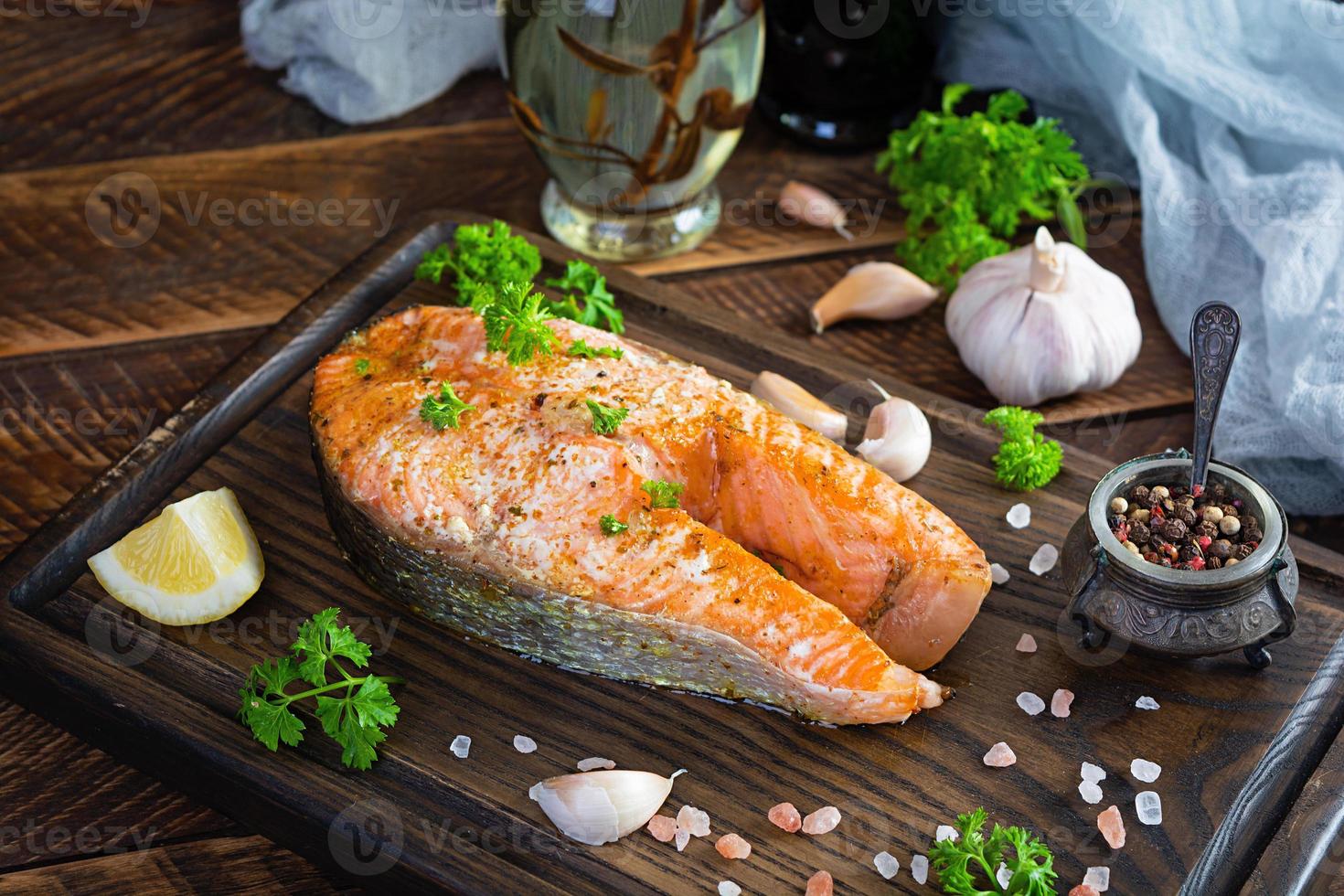 Gebackenes Lachssteak mit Kräutern auf Holzschneidebrett. gegrillter Lachs mit Salz und Pfeffer foto