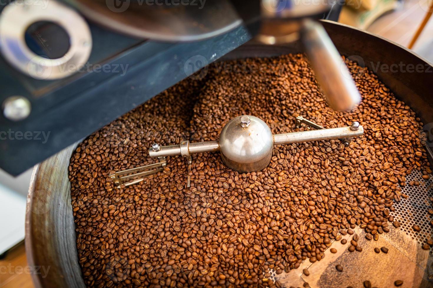 frisch geröstete aromatische Kaffeebohnen in einer modernen Kaffeeröstmaschine. kaffeeröster, kaffeebohnenhintergrund foto