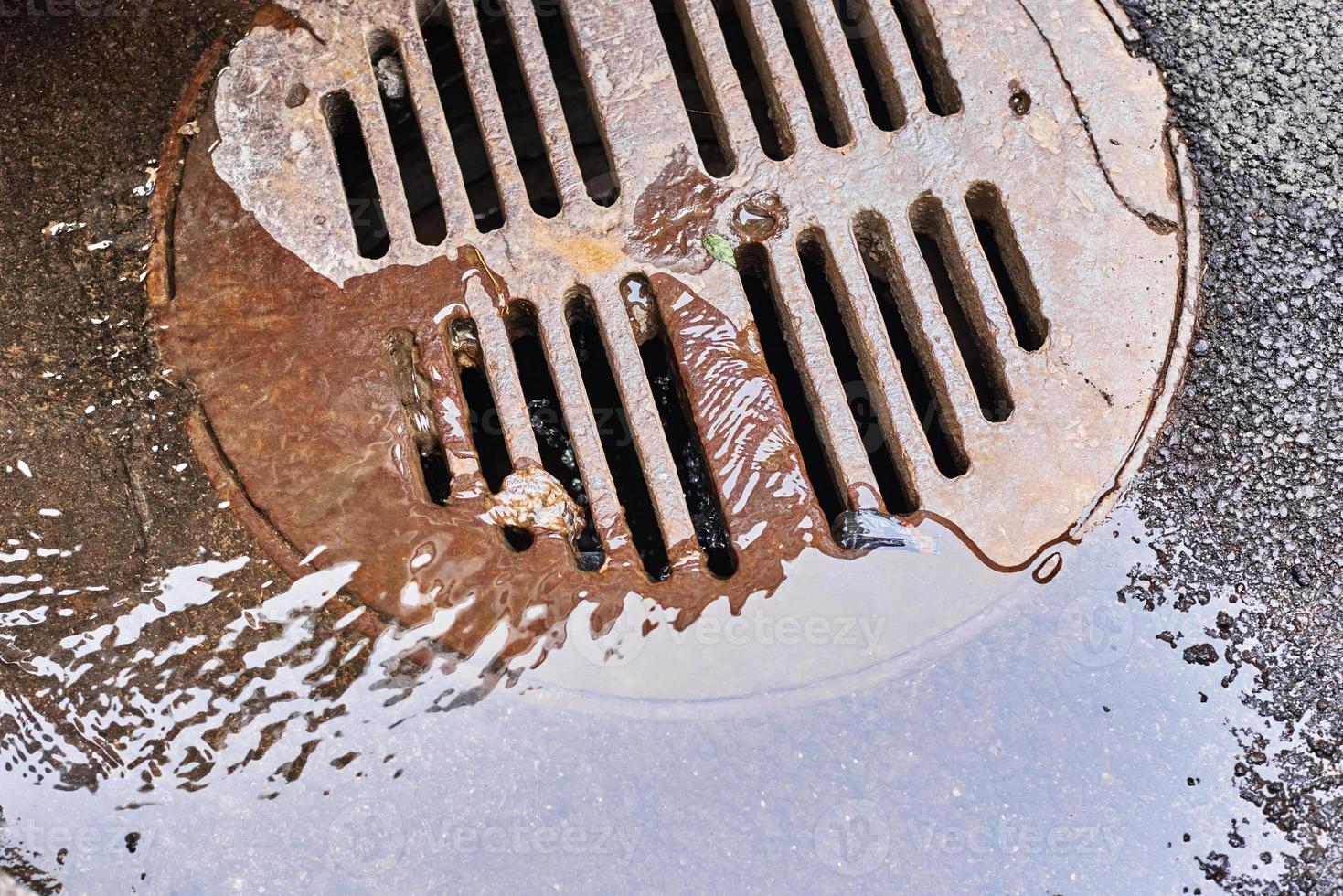 Wasser, das nach Regen auf der Stadtstraße in einen Kanalschacht abfließt foto