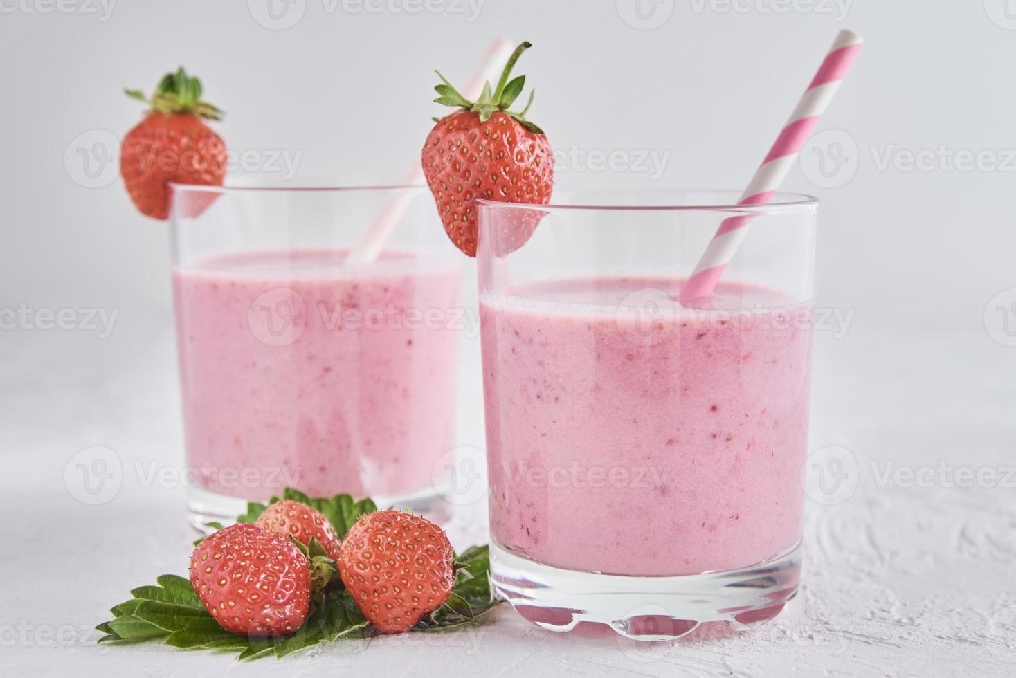 Erdbeermilchshake im Glas mit Stroh und frischen Beeren foto