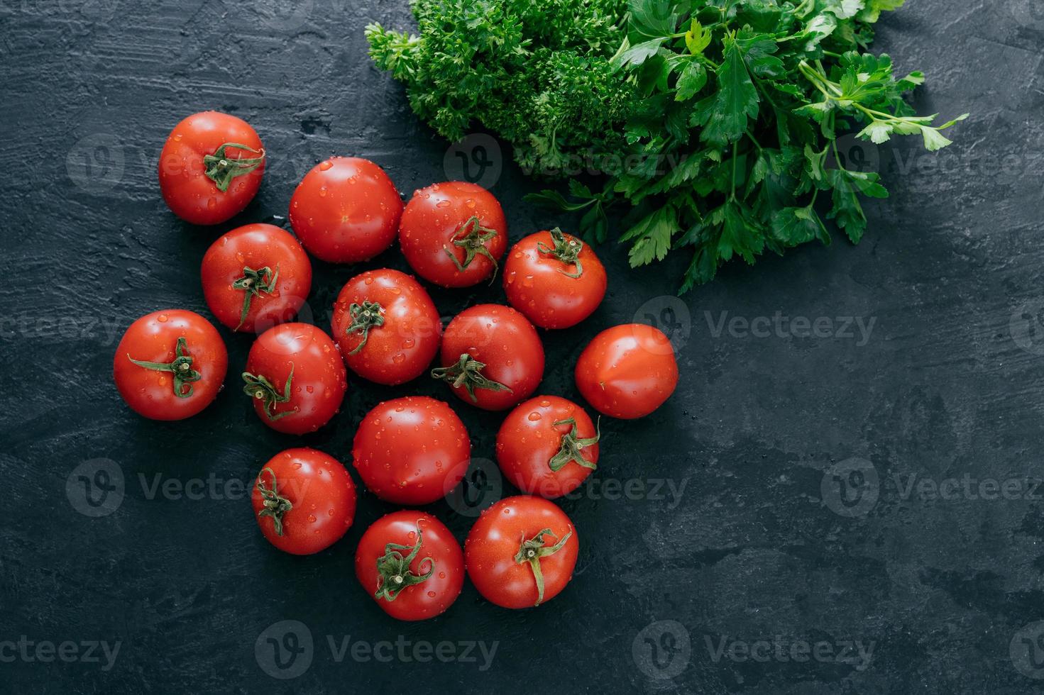 Draufsicht auf rote reife frische Tomaten mit grüner Petersilie auf dunklem Hintergrund. Vitamine und Ernährungskonzept. Platz kopieren. Rohkost foto