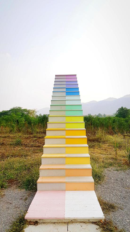 Regenbogen oder bunter Treppenweg oder Schritt im Park mit Grasfeld, grünem Baum und Himmelshintergrund. Vintage-Struktur und Retro-Objekt. Kunststruktur und gebaut. wachstums-, erfolgs- und auffüllkonzept foto