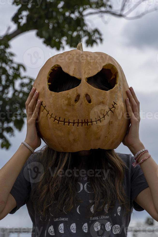 junge Frau mit Kürbiskopf nach dem Abschneiden und Aufsetzen eines Gesichts, Halloween, foto