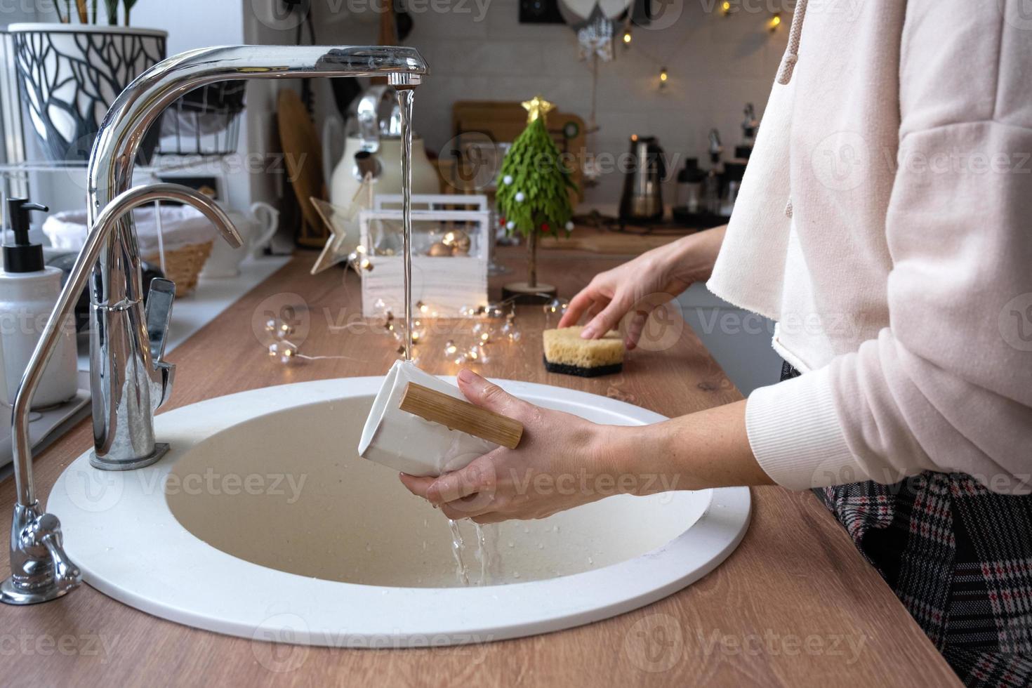 Reinigung der Küche vor den Weihnachts- und Neujahrsferien. Waschmittel, Trockenpulver, Schwamm, Handschuhe sind auf dem Waschbecken. festliches Dekor in der weißen Küche, gemütliches Interieur des Hauses foto