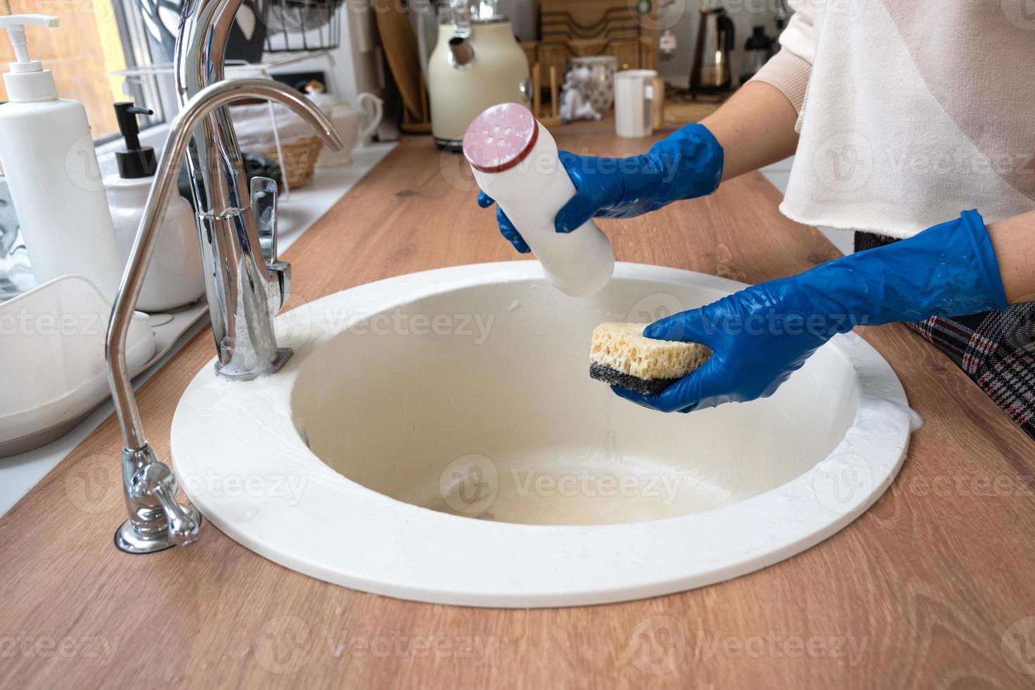 Reinigungsspüle in der Küche, Hand in Handschuhen und Schwamm, Reinigungsmittel, Trockenpulver. gemütliche Einrichtung des Hauses, Wiederherstellung der Ordnung, Sauberkeit, Desinfektion foto
