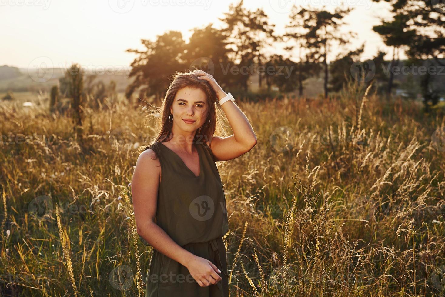 Porträt eines glücklichen Mädchens, das auf dem von Sonnenlicht beleuchteten Feld steht foto