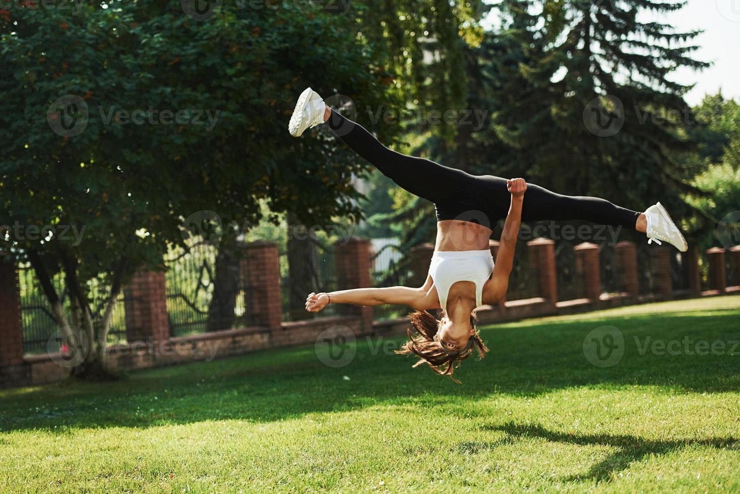 verrückte Stunts. junge Frau, die im Park Akrobatik- und Parkour-Tricks macht foto