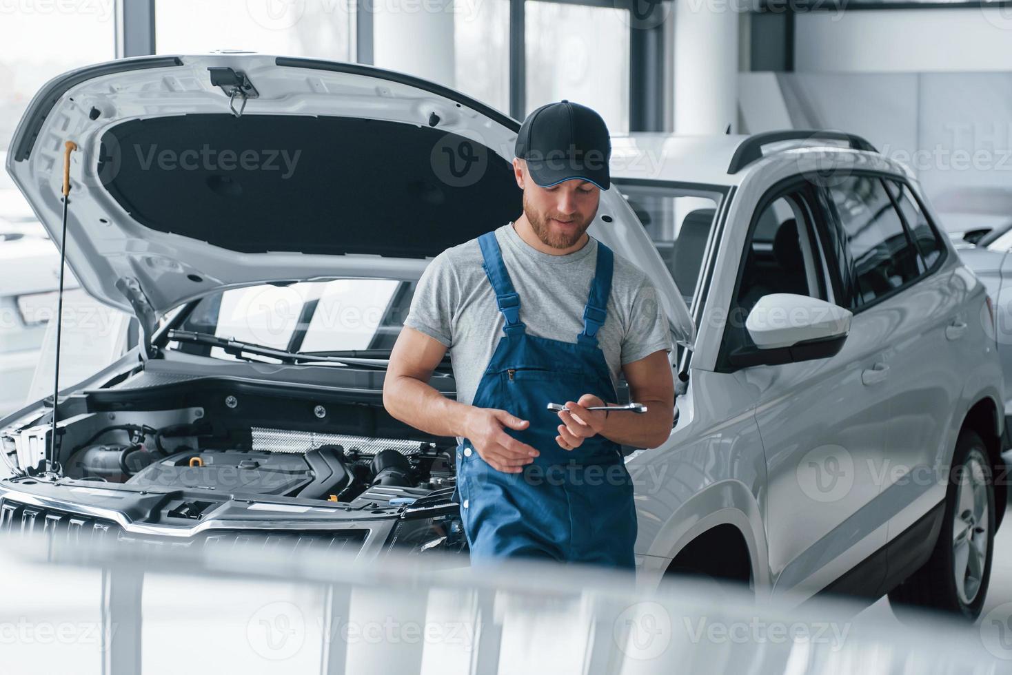 Ruhen am Arbeitsplatz. Mitarbeiter in blauer Uniform steht im Automobilsalon foto