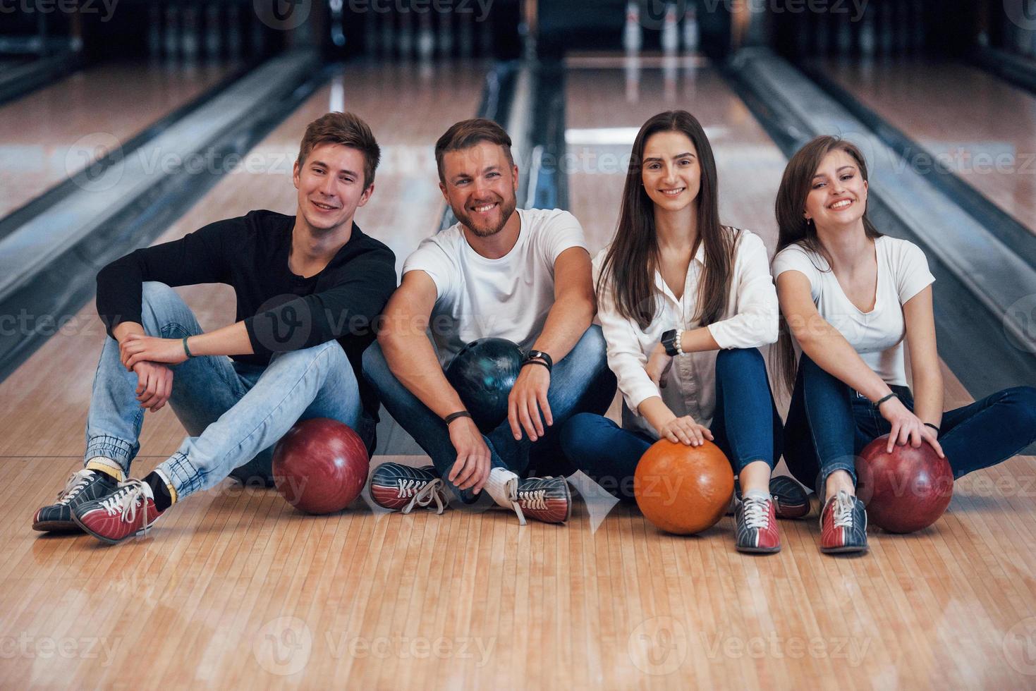 gute Zeit verbringen. Junge, fröhliche Freunde haben an ihren Wochenenden Spaß im Bowlingclub foto