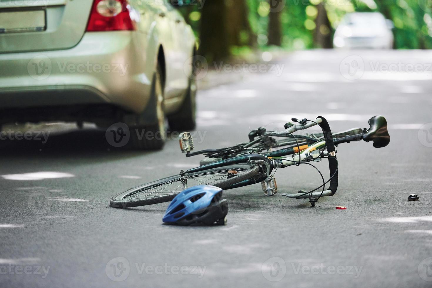 fahrrad- und silberfarbener autounfall auf der straße im wald tagsüber foto