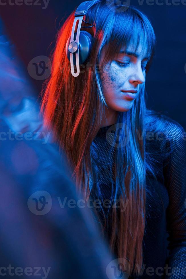 Liebe zum Detail. Studioaufnahme im dunklen Studio mit Neonlicht. Porträt eines jungen Mädchens foto