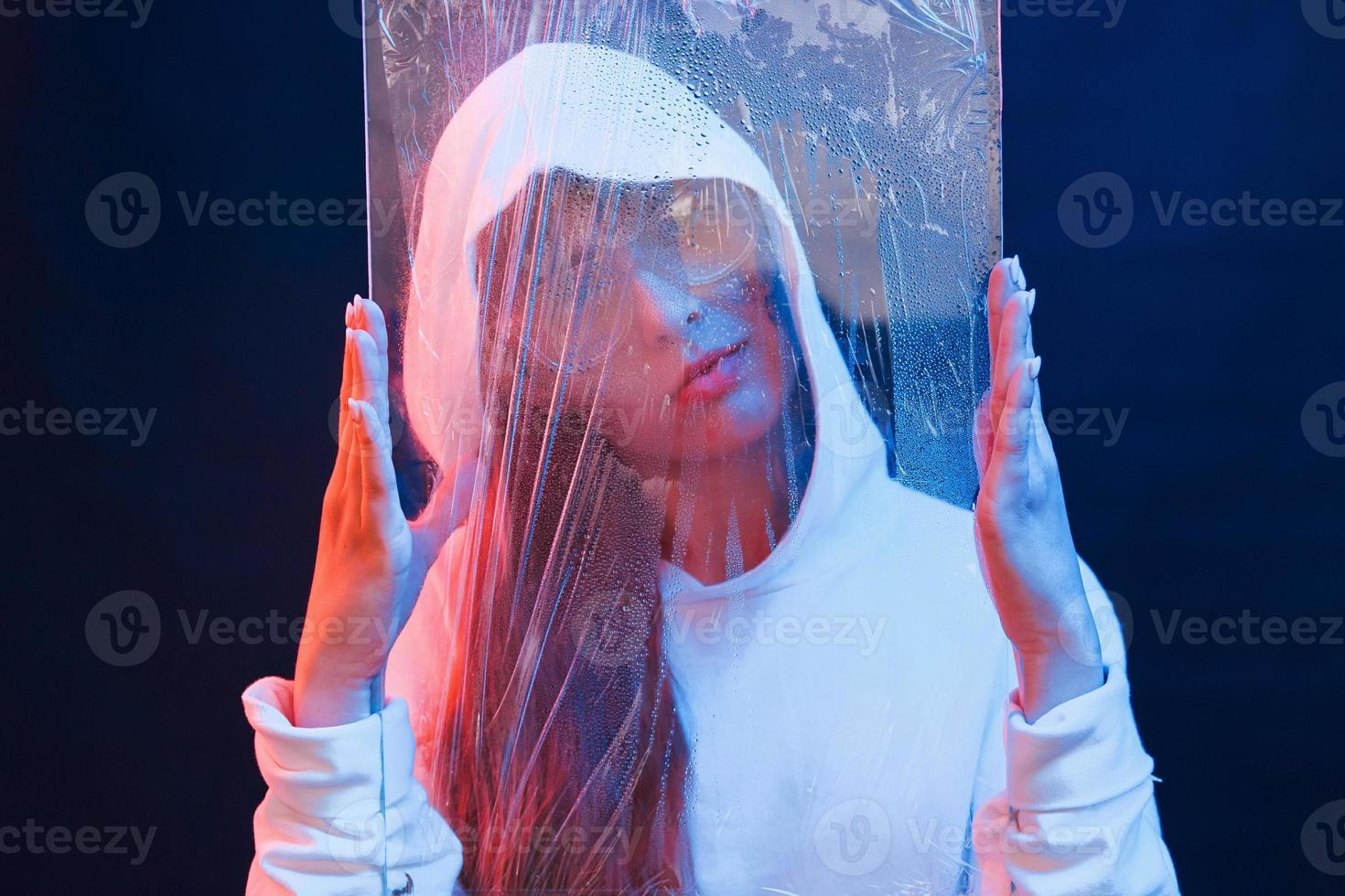 Glas halten. Studioaufnahme im dunklen Studio mit Neonlicht. Porträt eines jungen Mädchens foto