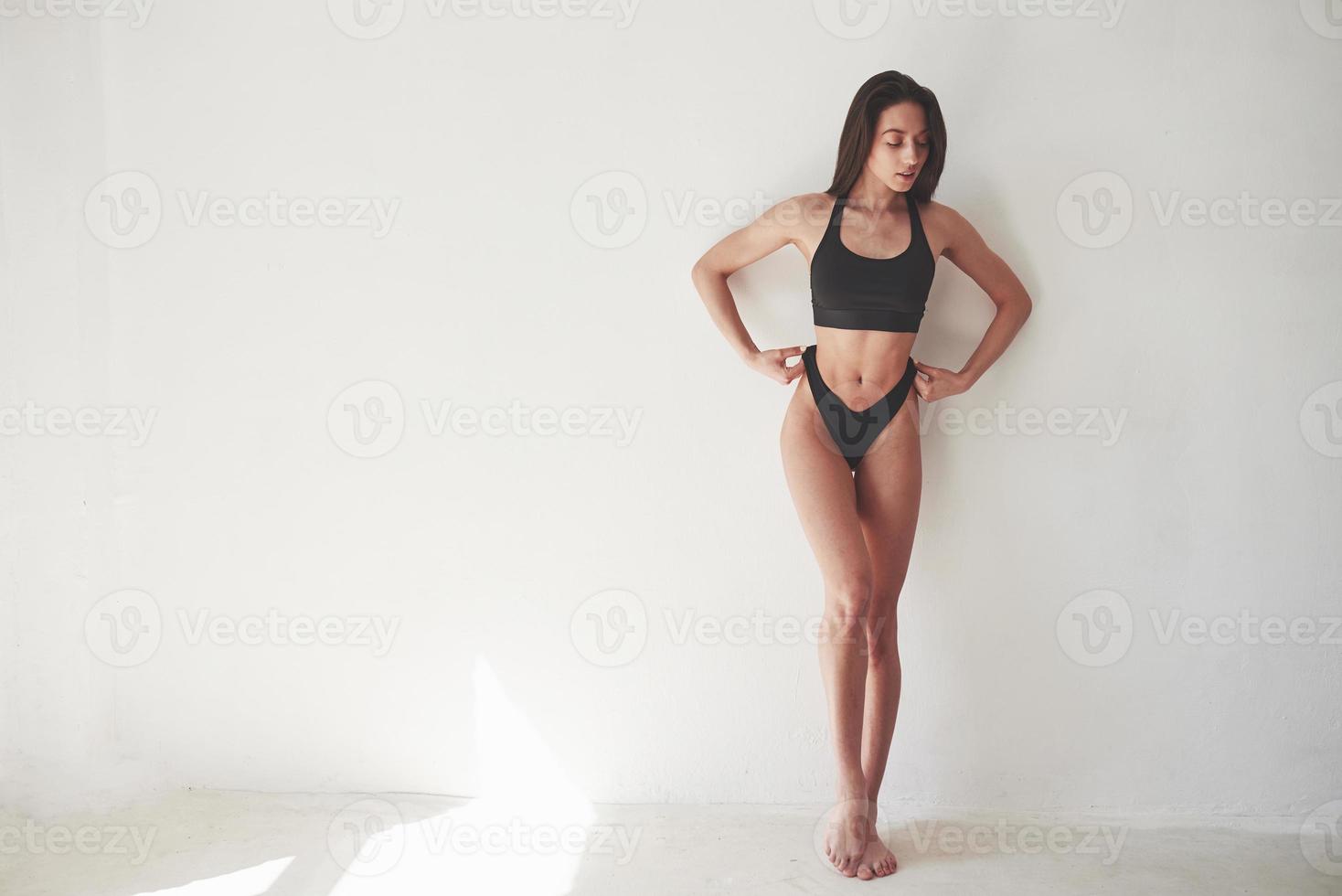 schlanker Körpertyp. Kaukasische hübsche Frau steht vor weißem Hintergrund im leeren Raum foto