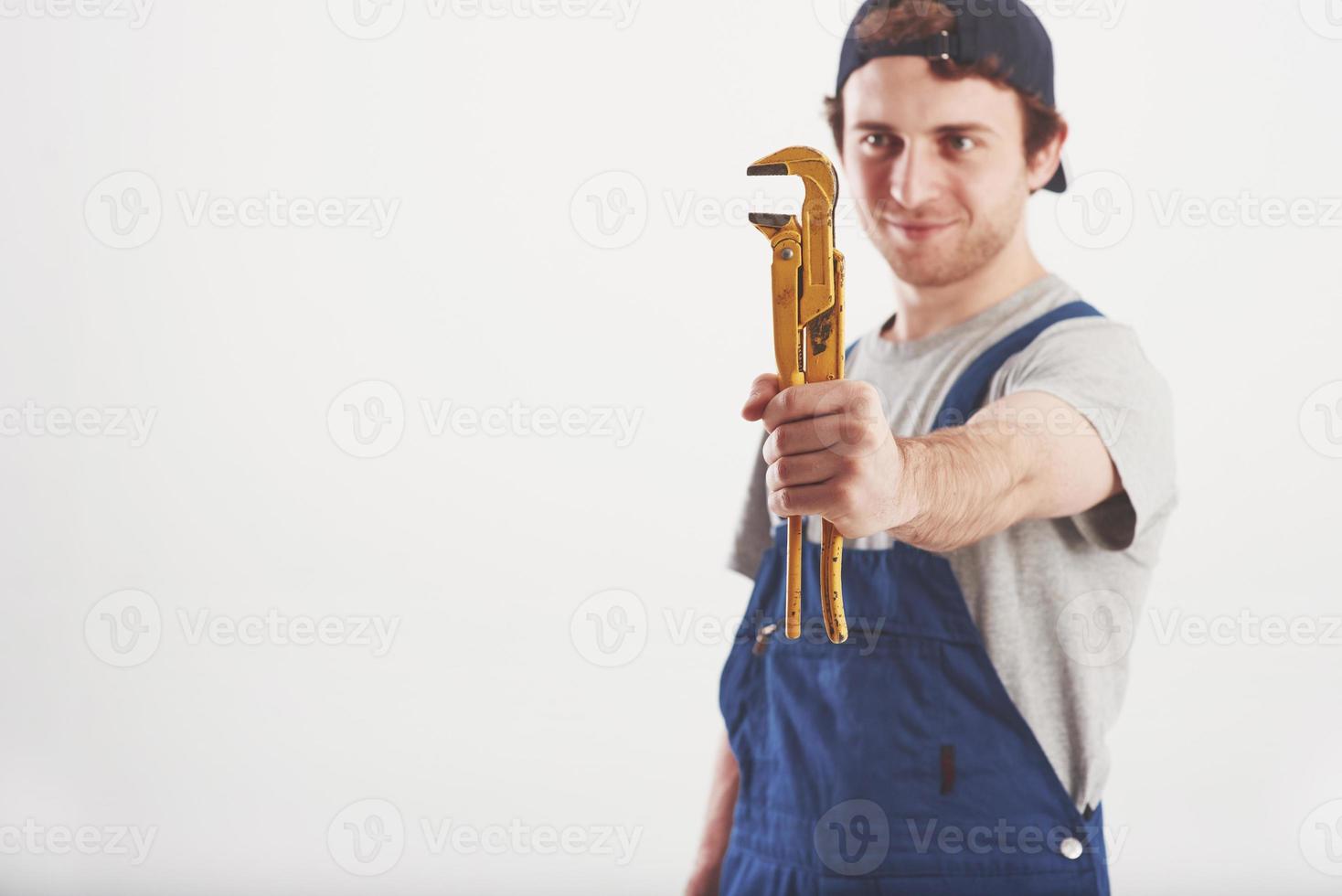 unersetzliche Sache. Mann in blauer Uniform steht vor weißem Hintergrund im Studio foto