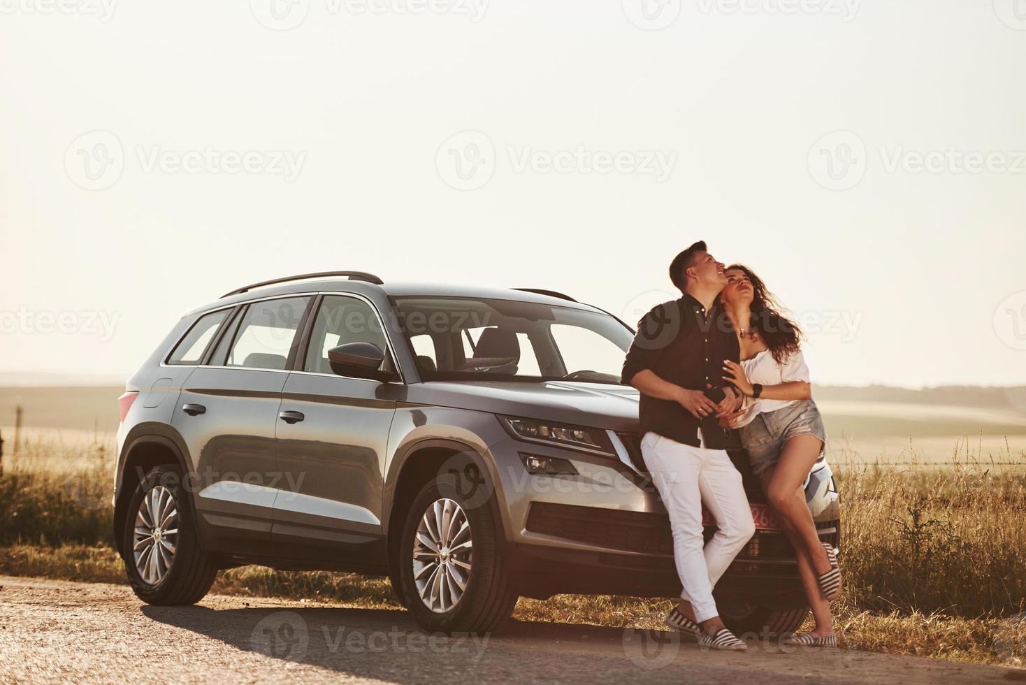 Sieh nach oben. Schönes Paar in der Nähe ihres neuen modernen Autos am Wochenende foto