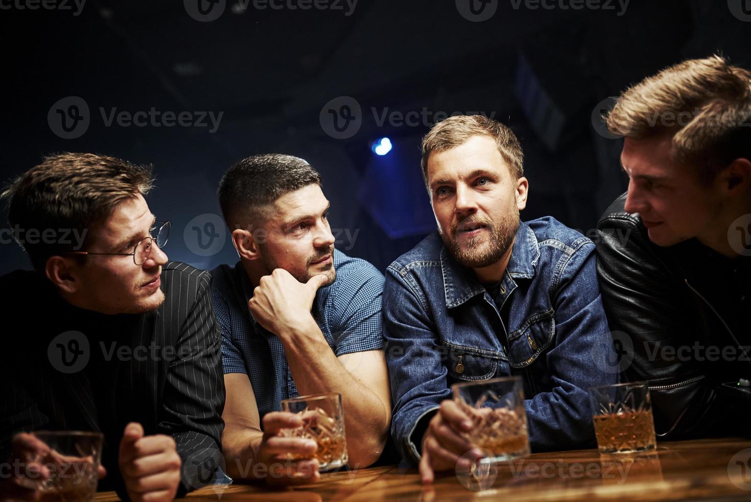 Vorderansicht. freunde ruhen sich mit alkohol in den händen in der kneipe aus. Gespräch haben foto