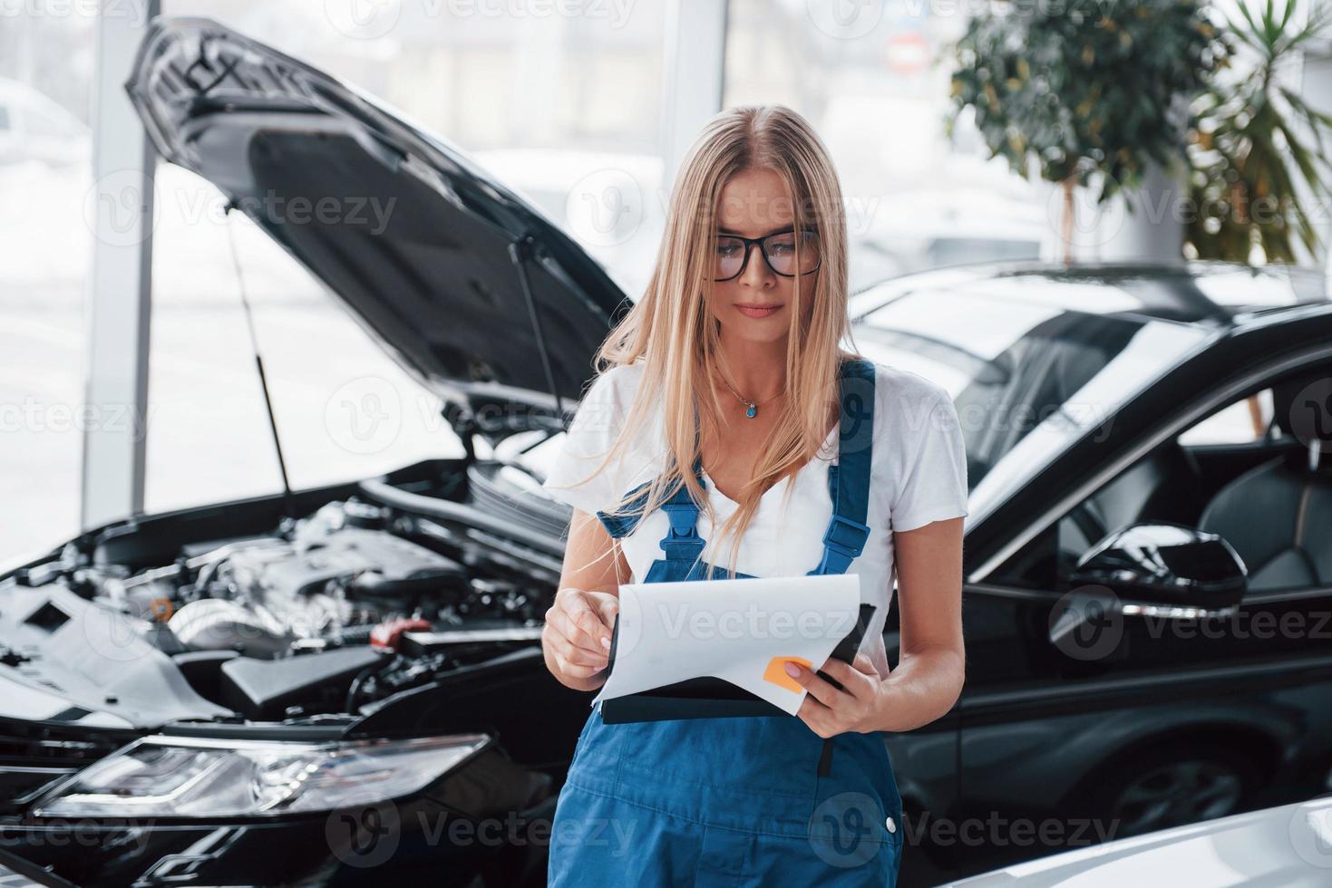 was wir heute bekommen haben. manager mit notizblock, im weißen hemd und in blauer uniform steht mit aufgesetzter verdeck vor auto foto