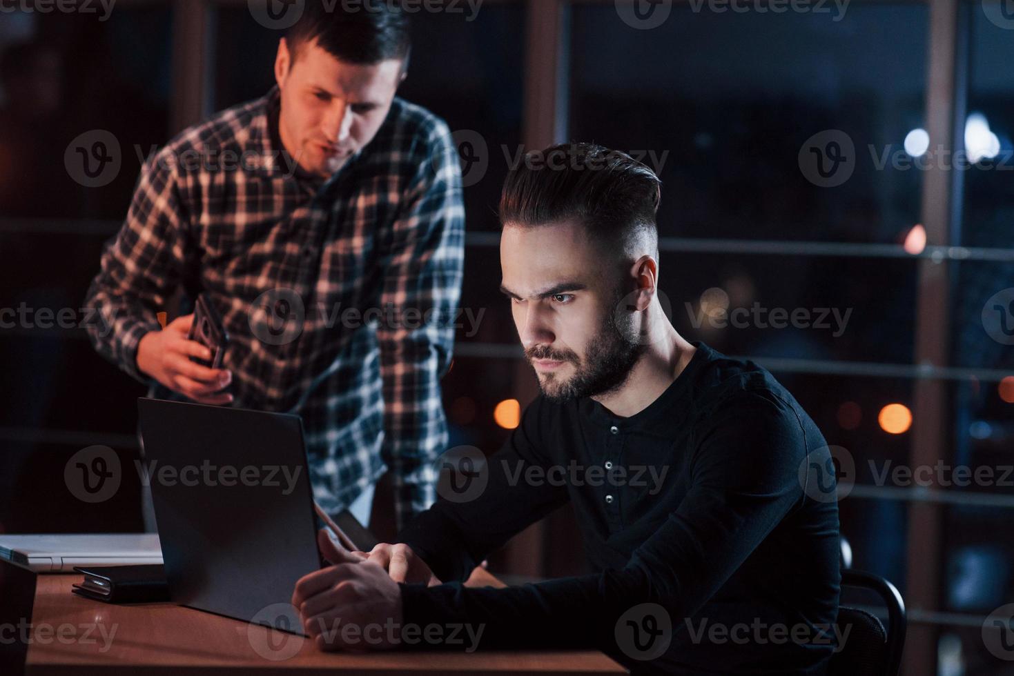 komm her und hilf mir. ein team junger geschäftsleute arbeitet nachts im büro an ihrem projekt foto